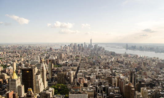 Panorama-Blick über Manhattan mit dem One World Trade Center im Zentrum, umgeben von der gewaltigen Ausdehnung der Stadt und dem Hudson River. Perfekt als Leinwandbild oder Poster, um das Gefühl von Urbanität und Weite in Ihr Zuhause zu bringen.

